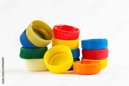Multicolored plastic bottle caps are scattered on a white background. Plastic recycle place for text.