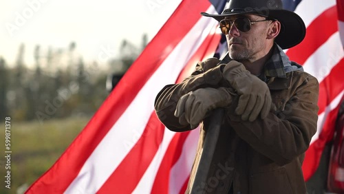 Cowboy Against Backdrop of US Flag Ruffling in the Wind