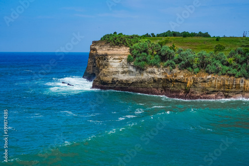 Pantai Klayar or Klayar Beach with rocks and strong waves against the blue sky