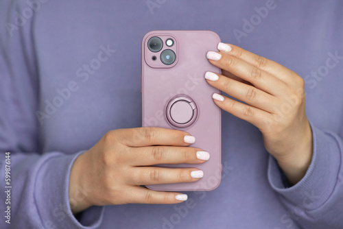 Puple silicone case with ring on new mobile phone in female hands. Faceless woman make a photo on smartphone. Monochrome concept