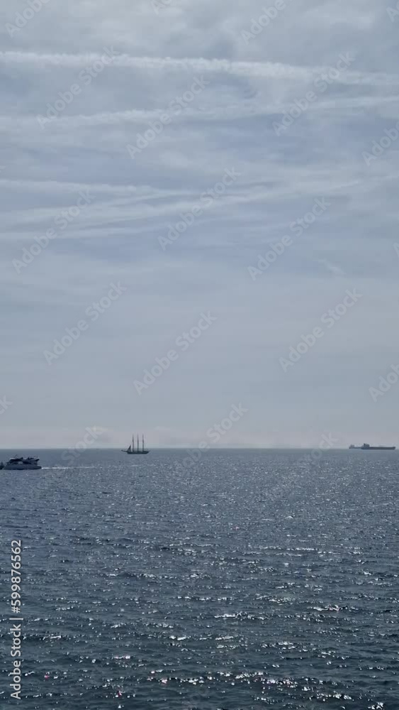 The ships are on the roadstead on the horizon in the Mediterranean near Barcelona. Pleasure boat follows along the coast. Spain The ships are on the roadstead on the horizon in the Mediterranean near Barcelona. Pleasure boat follows along the coast. Spain