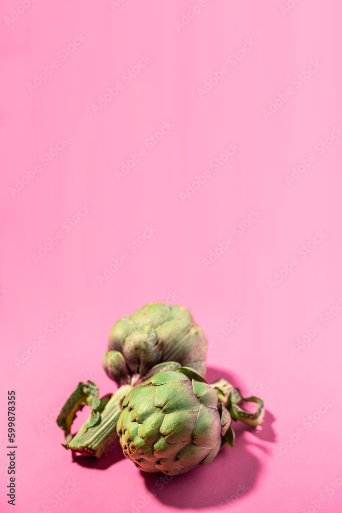 Fototapeta premium Fresh green artichokes isolated on pink background