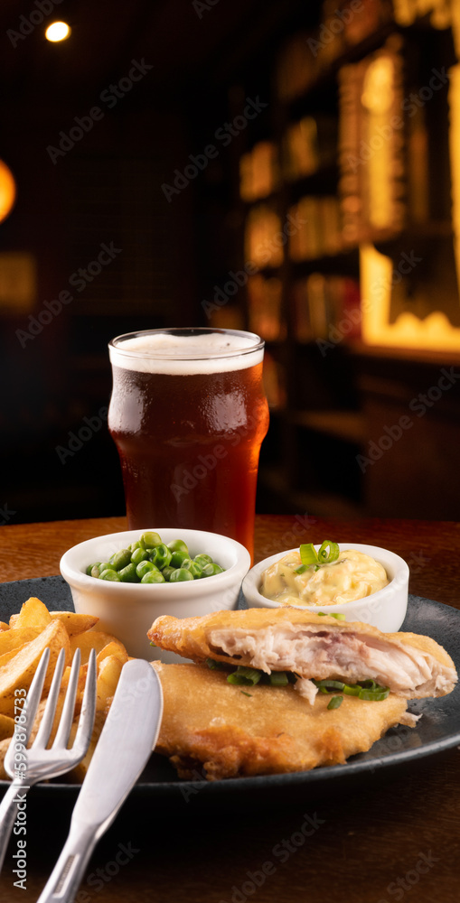 plate of fish and chips with sliced fried fish and pub table close-up blurred in the background plate of fish and chips with sliced fried fish and pub table close-up blurred in the background