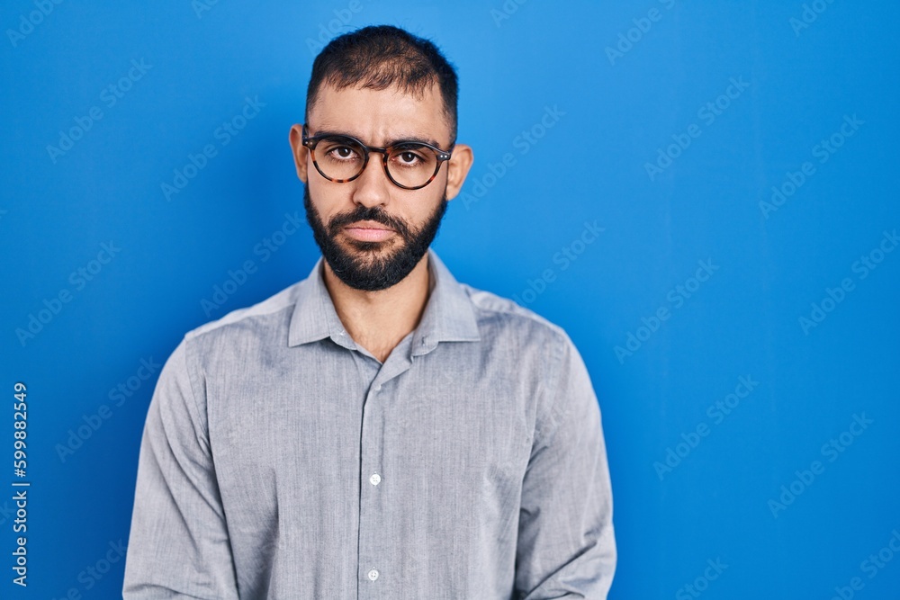 Middle east man with beard standing over blue background skeptic and nervous, frowning upset because of problem. negative person. Middle east man with beard standing over blue background skeptic and nervous, frowning upset because of problem. negative person.