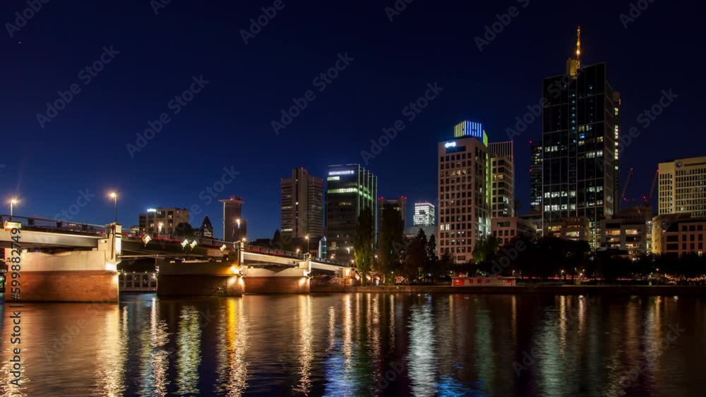 Stunning timelapse of Frankfurt's skyline at night featuring a bridge, skyscrapers, traffic with light trails, and dazzling city illumination reflecting in the river. Stunning timelapse of Frankfurt's skyline at night featuring a bridge, skyscrapers, traffic with light trails, and dazzling city illumination reflecting in the river.