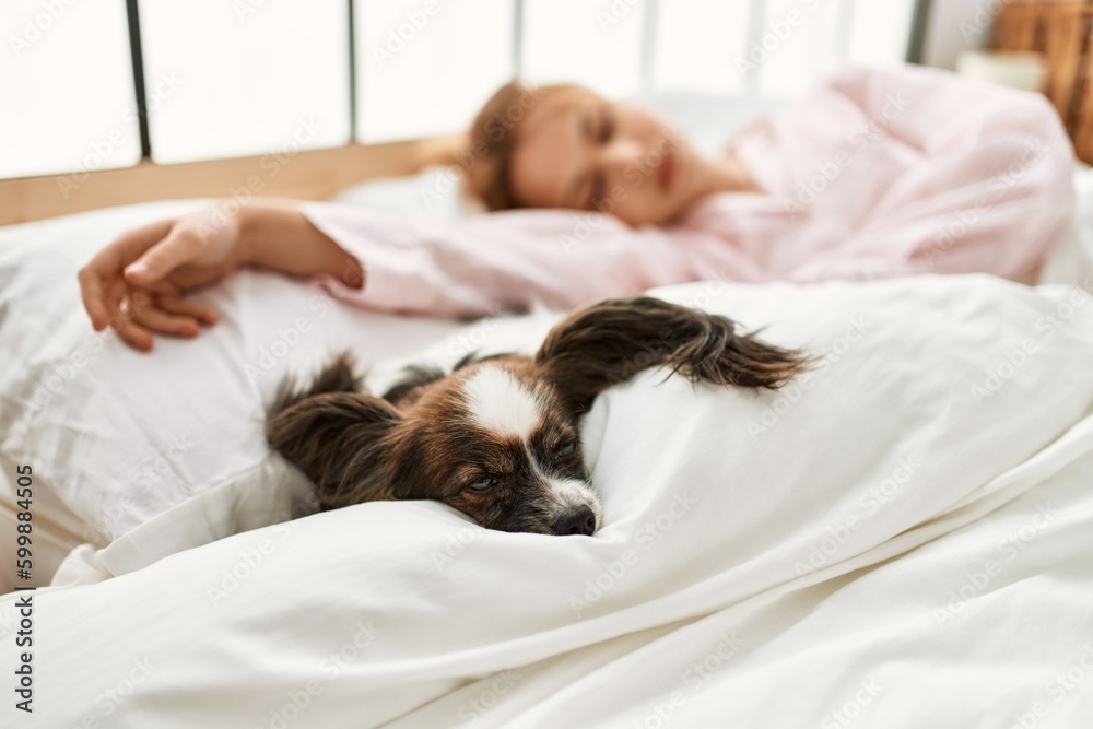 Young caucasian woman lying on bed with dog sleeping at bedroom Young caucasian woman lying on bed with dog sleeping at bedroom