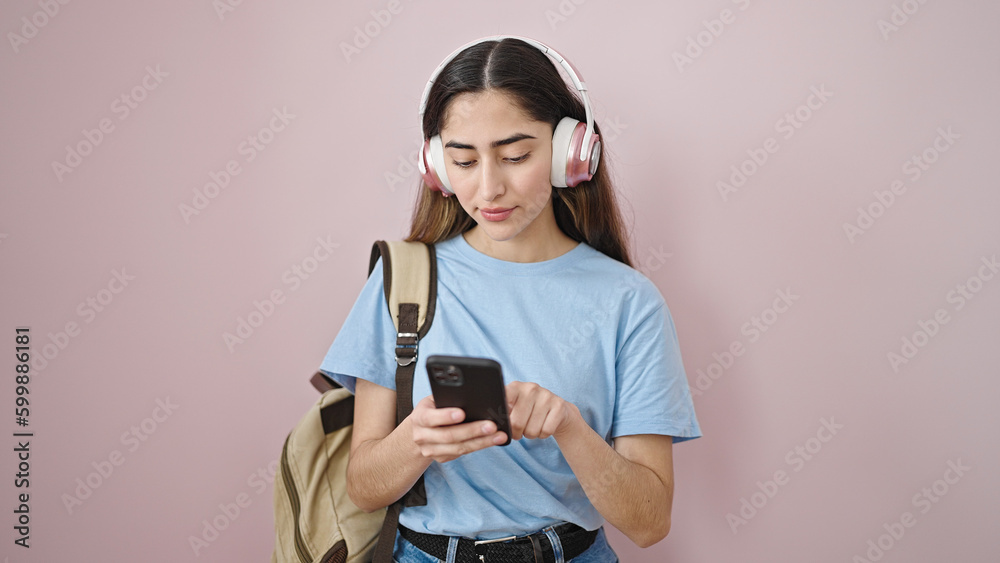Young beautiful hispanic woman student using smartphone and headphones at street
