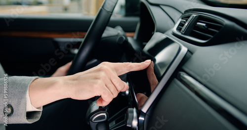 Close up of female hand driver entering an address into the navigation system in modern car. Female hand touches navigation on car monitor screen