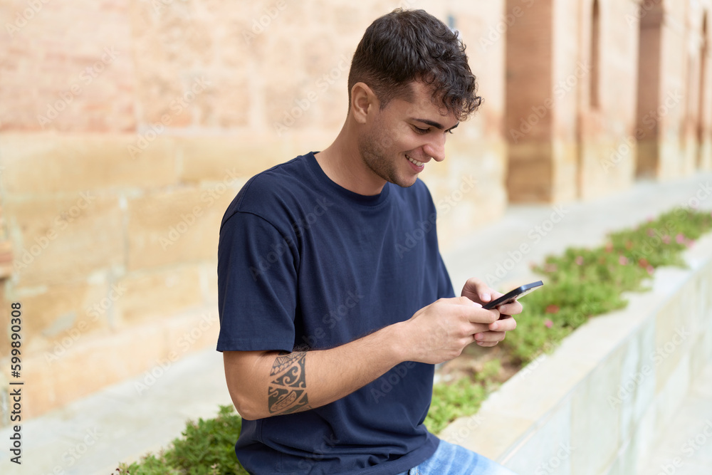 Obraz premium Young hispanic man smiling confident using smartphone at street