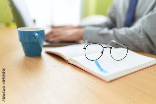 Young hispanic man business worker sitting on table working at office