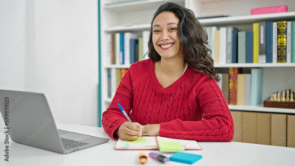 Young beautiful hispanic woman student using laptop writing notes at library university Young beautiful hispanic woman student using laptop writing notes at library university
