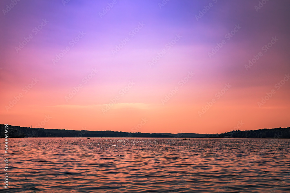 Obraz premium Purple sunset over the lake with reflection on the water ripples