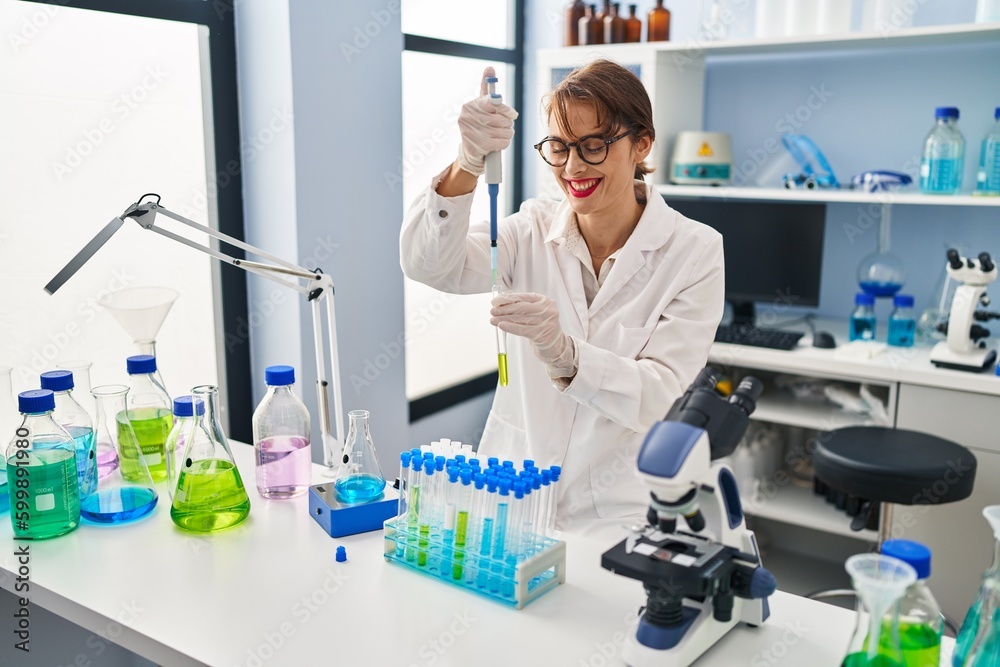 Young caucasian woman wearing scientist uniform using pipette at laboratory