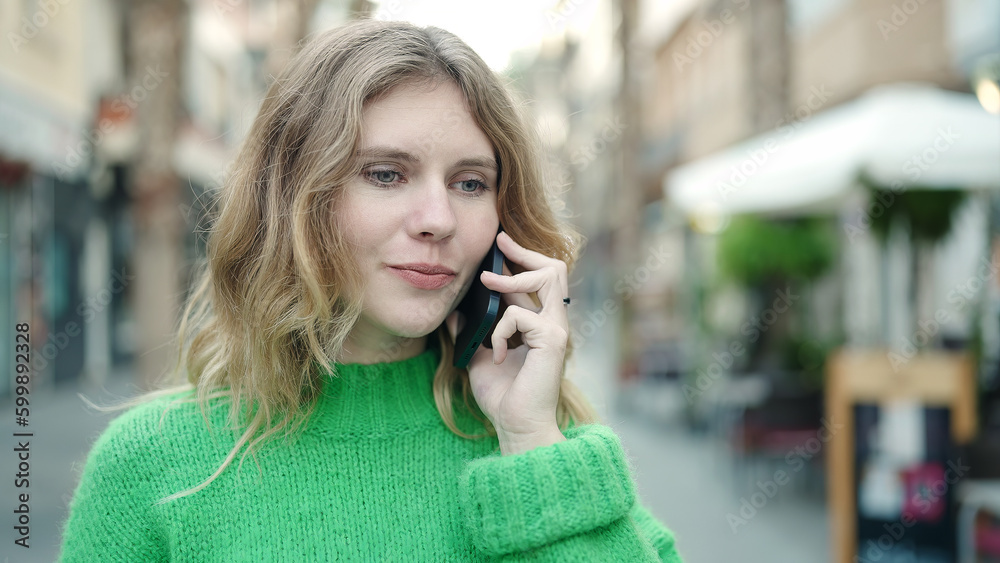 Young blonde woman talking on the smartphone with relaxed expression at coffee shop terrace Young blonde woman talking on the smartphone with relaxed expression at coffee shop terrace