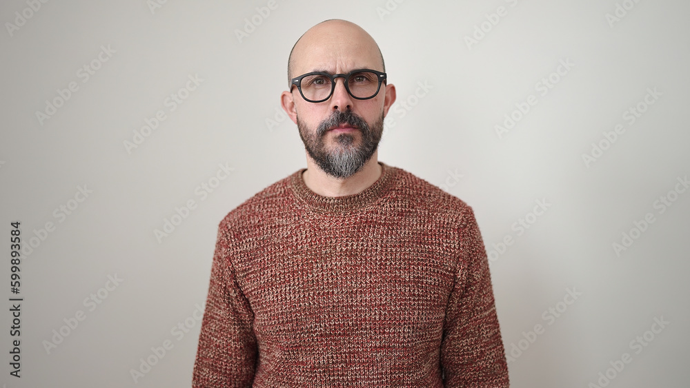 Fototapeta premium Young bald man standing with serious expression over isolated white background