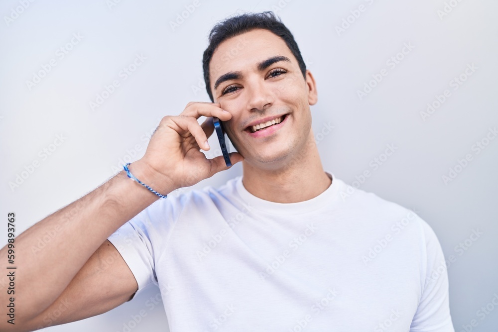 Young hispanic man smiling confident talking on the smartphone over isolated white background Young hispanic man smiling confident talking on the smartphone over isolated white background