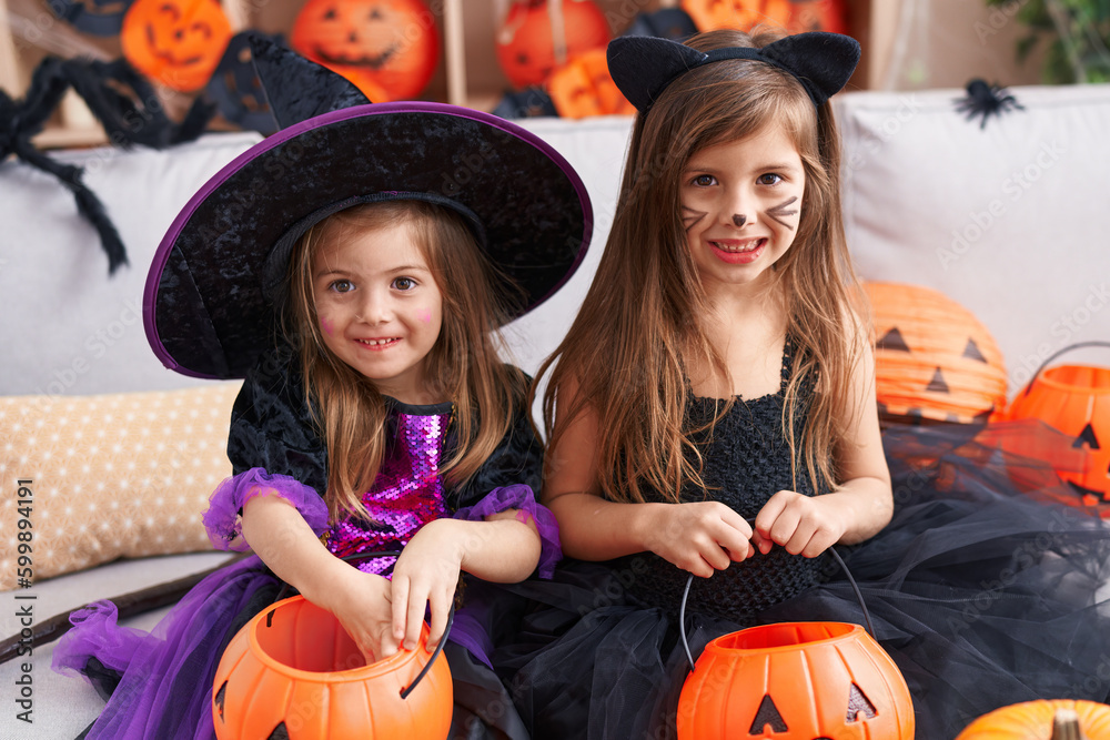 Adorable girls having halloween party holding pumpkin basket at home Adorable girls having halloween party holding pumpkin basket at home