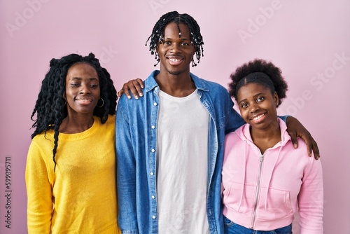 Group of three young black people standing together over pink background with a happy and cool smile on face. lucky person.