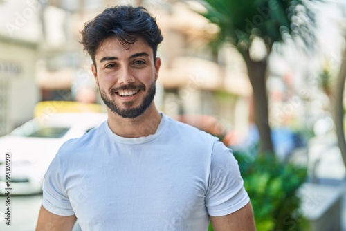 Young hispanic man smiling confident standing at street