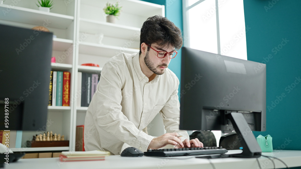 Young hispanic man student using computer studying at library university Young hispanic man student using computer studying at library university