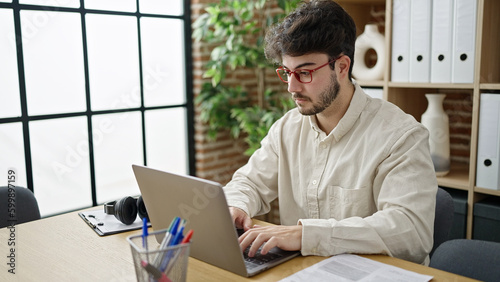 Young hispanic man business worker using laptop working at office