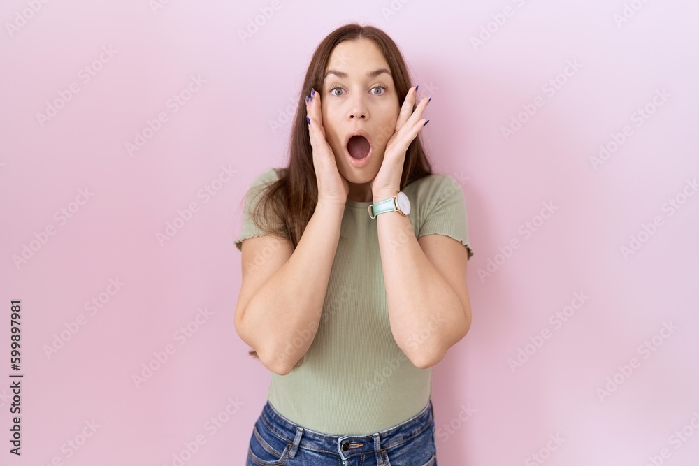 Beautiful brunette woman standing over pink background afraid and shocked, surprise and amazed expression with hands on face Beautiful brunette woman standing over pink background afraid and shocked, surprise and amazed expression with hands on face