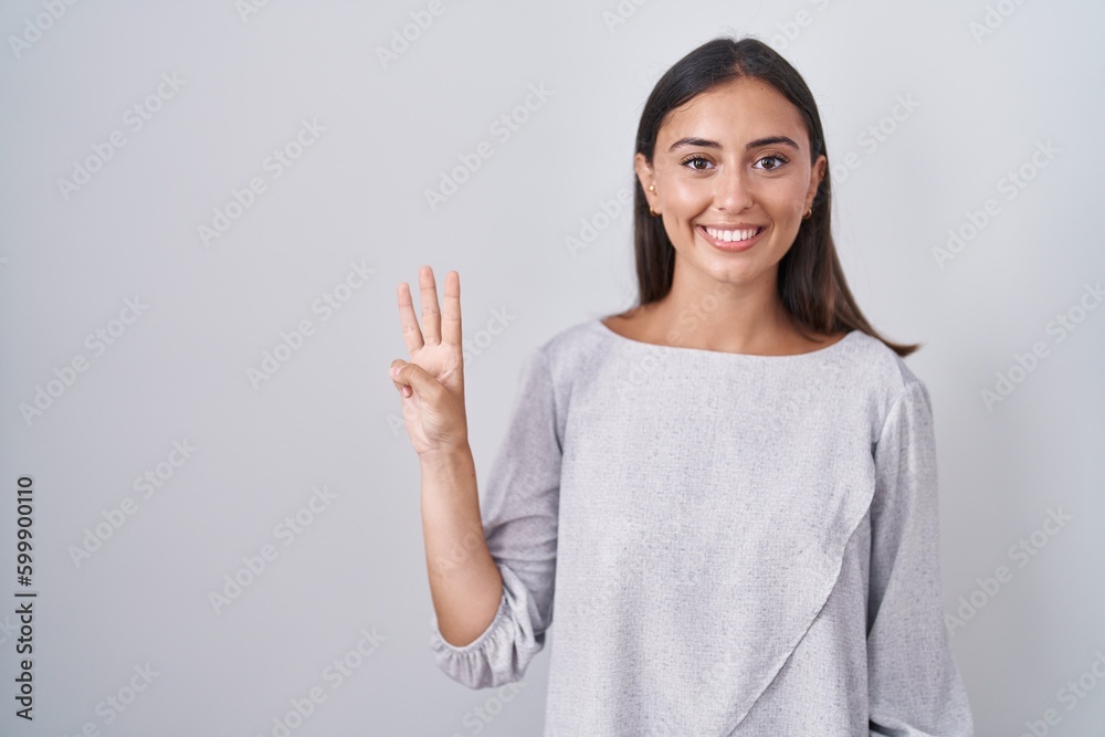 Young hispanic woman standing over white background showing and pointing up with fingers number three while smiling confident and happy. Young hispanic woman standing over white background showing and pointing up with fingers number three while smiling confident and happy.