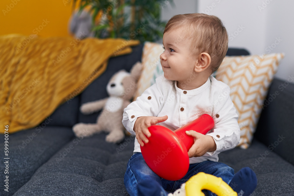 Adorable caucasian boy playing hoops game sitting on sofa at home Adorable caucasian boy playing hoops game sitting on sofa at home