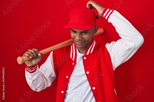 Photography Young hispanic man playing baseball holding bat confuse and wondering about question