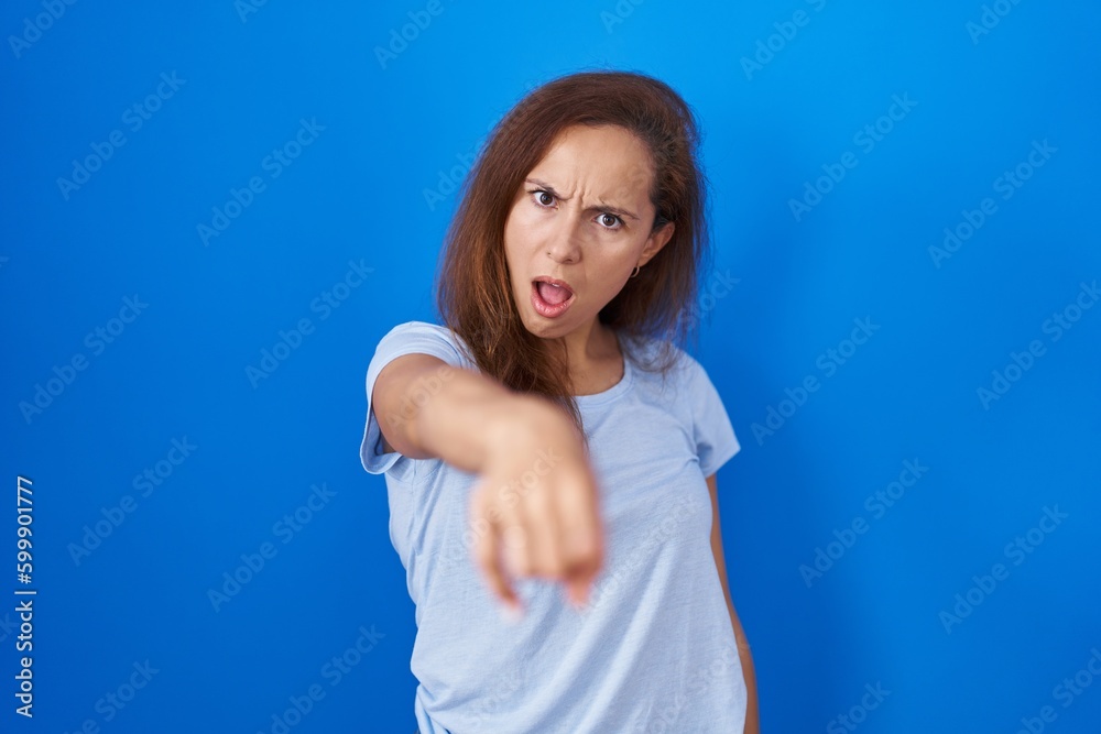 Brunette woman standing over blue background pointing displeased and frustrated to the camera, angry and furious with you Brunette woman standing over blue background pointing displeased and frustrated to the camera, angry and furious with you