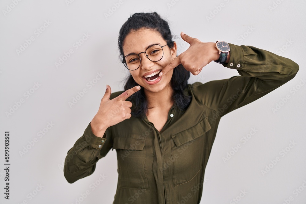 Hispanic woman with dark hair standing over isolated background smiling cheerful showing and pointing with fingers teeth and mouth. dental health concept. Hispanic woman with dark hair standing over isolated background smiling cheerful showing and pointing with fingers teeth and mouth. dental health concept.