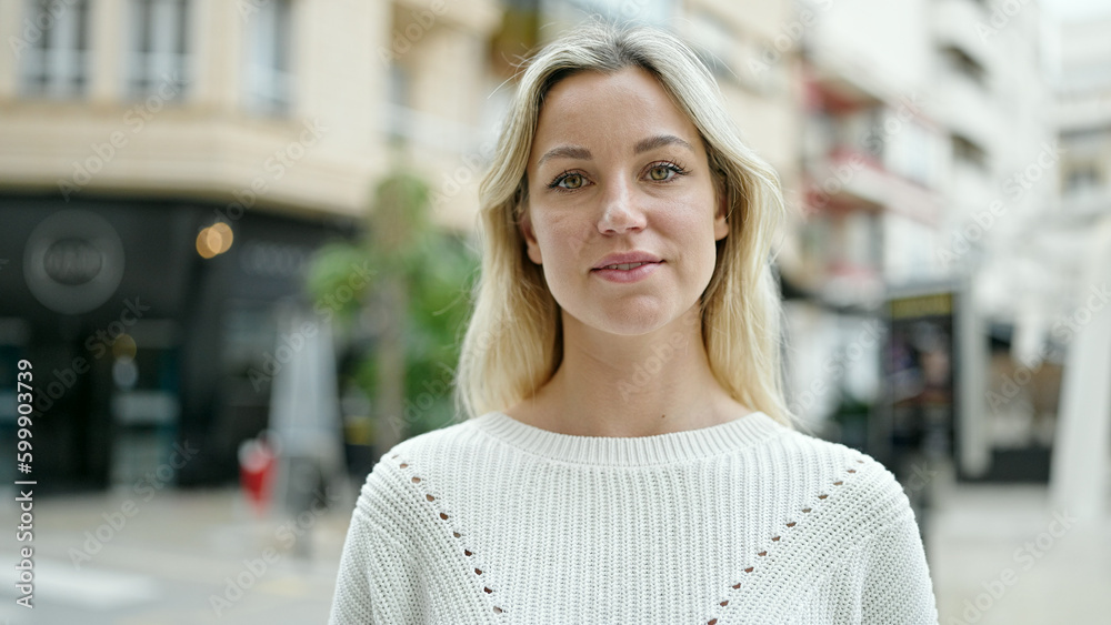 Young blonde woman standing with serious expression at street