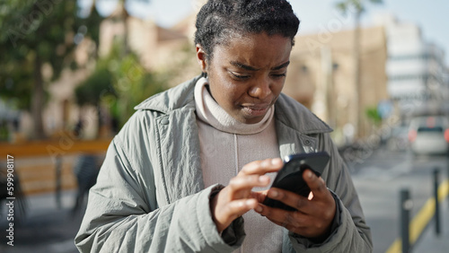 African american woman using smartphone with serious expression at park