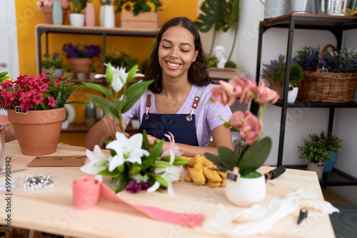 Young african american woman florist make bouquet of flowers at flower shop