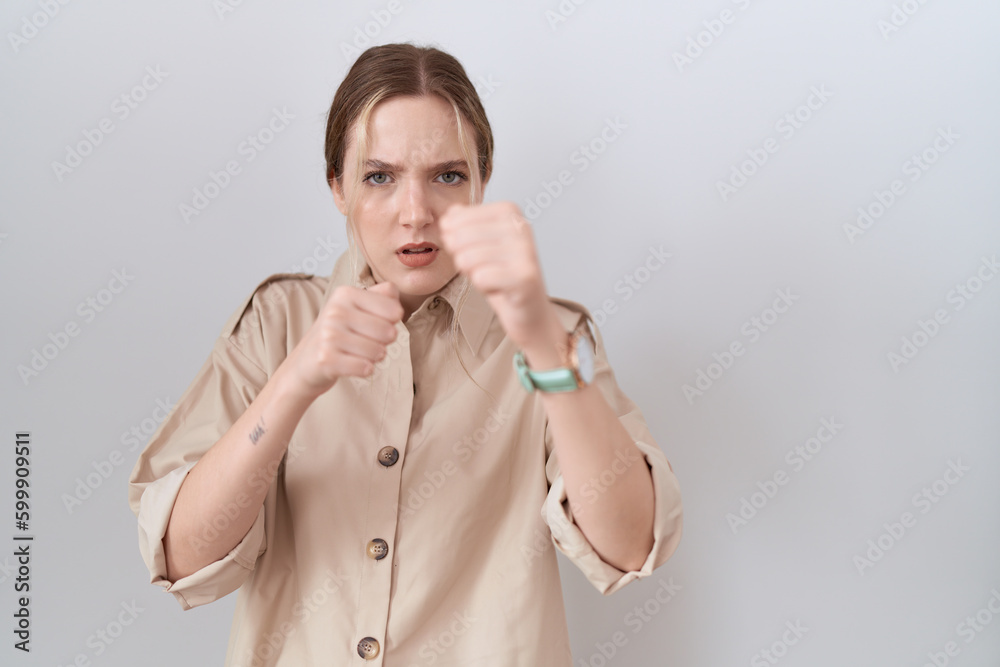 Young caucasian woman wearing casual shirt punching fist to fight, aggressive and angry attack, threat and violence Young caucasian woman wearing casual shirt punching fist to fight, aggressive and angry attack, threat and violence