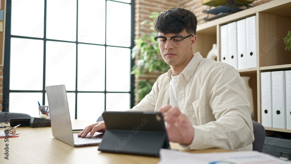 Young hispanic man business worker using laptop and touchpad working at office