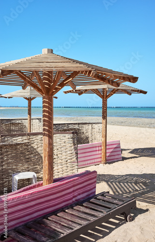 Wooden sun umbrellas  sun beds and windscreens on beach.