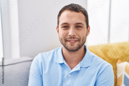Young man smiling confident sitting on sofa at home