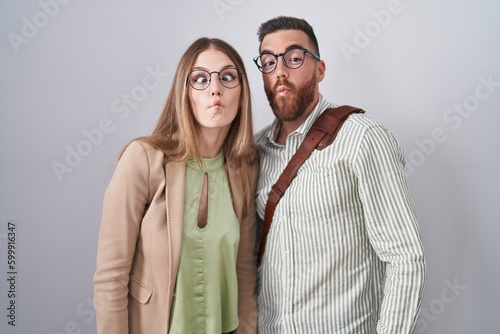 Young couple standing over white background making fish face with lips, crazy and comical gesture. funny expression.