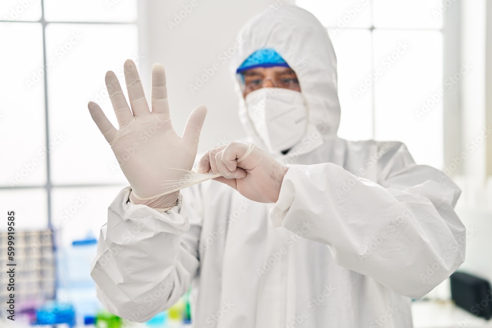 Young latin man scientist wearing covid protection uniform and gloves at laboratory Young latin man scientist wearing covid protection uniform and gloves at laboratory