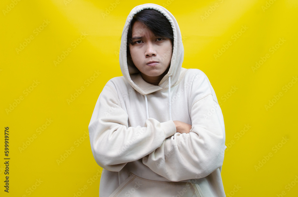 Obraz premium an Asian young man in beige hoodie, threatening, accusing, and looking for fight. A hysterical, mad depressed indonesian young man hand, shouts and screams loudly.