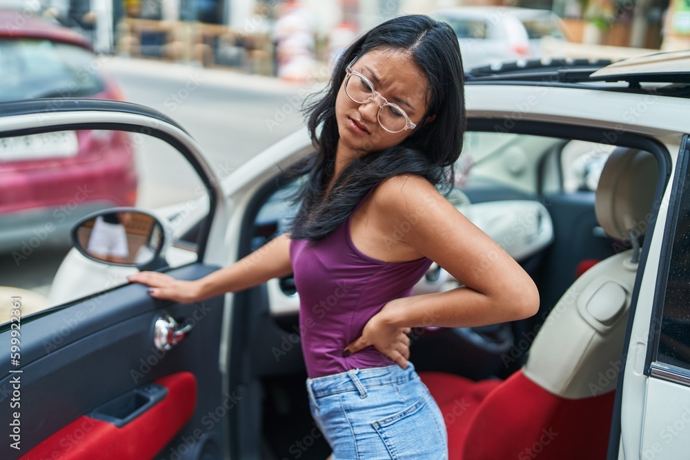 Young chinese woman suffering for backache standing at street Young chinese woman suffering for backache standing at street