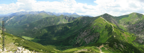 Panorama of Polish Tatra Mountains from Mount Giewont on a sunny summer day. On the left, in the distance, the High Tatras, on the right - the yellow tourist trail to Kopa Kondracka.