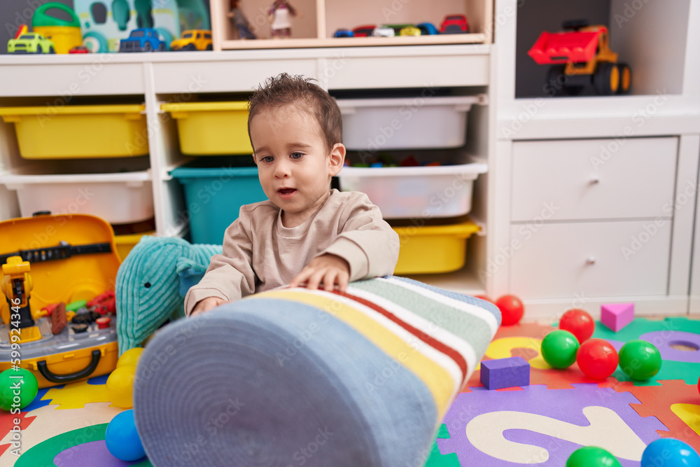 Adorable hispanic boy playing with balls sitting on floor at kindergarten Adorable hispanic boy playing with balls sitting on floor at kindergarten