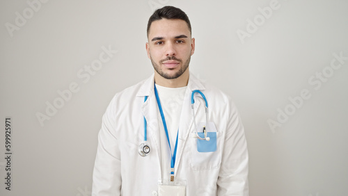 Young hispanic man doctor standing with serious expression over isolated white background