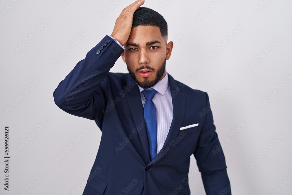 Young hispanic man wearing business suit and tie surprised with hand on head for mistake, remember error. forgot, bad memory concept. Young hispanic man wearing business suit and tie surprised with hand on head for mistake, remember error. forgot, bad memory concept.