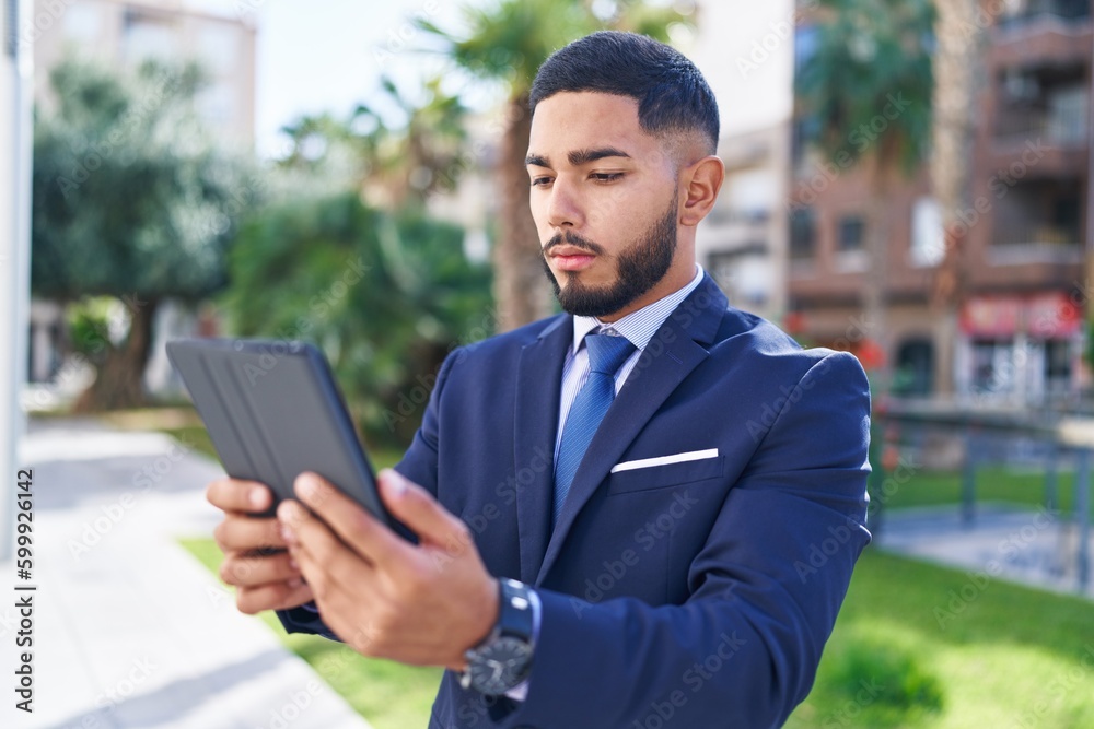 Young latin man business worker using touchpad with serious expression at park Young latin man business worker using touchpad with serious expression at park