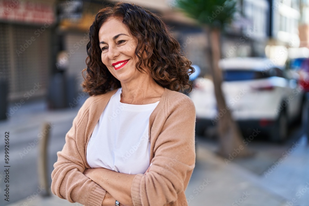 Middle age hispanic woman smiling happy with crossed arms outdoors
