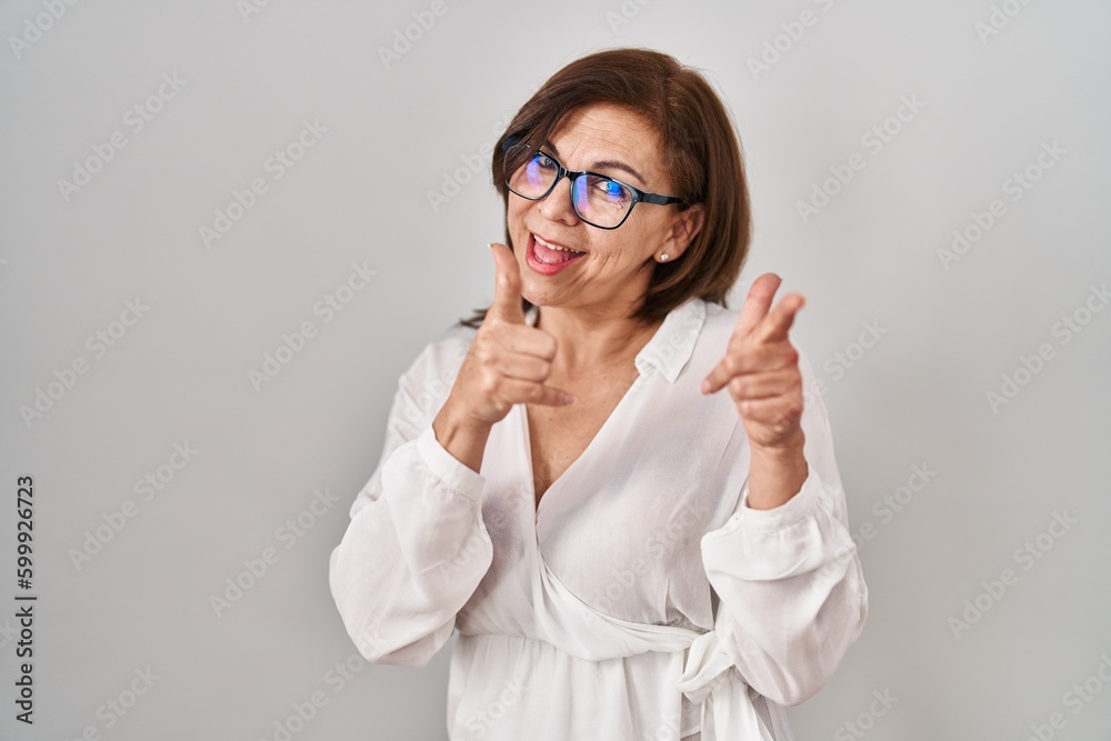 Middle age hispanic woman standing over isolated background pointing fingers to camera with happy and funny face. good energy and vibes.
