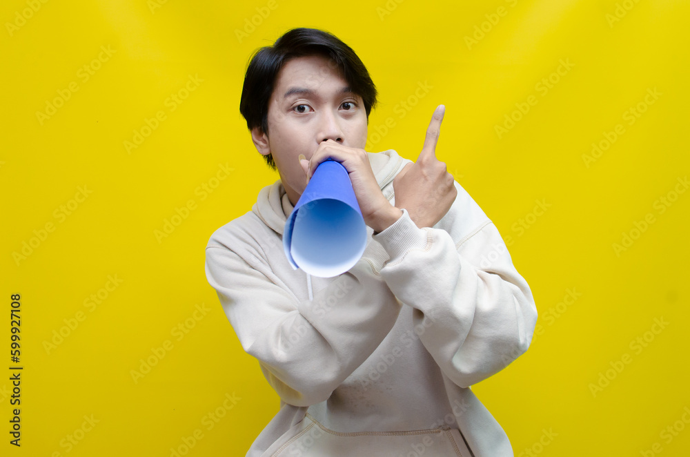 Asian man pointing finger and promoting something while shouting to paper megaphone. best for sale, discount, and promotion content